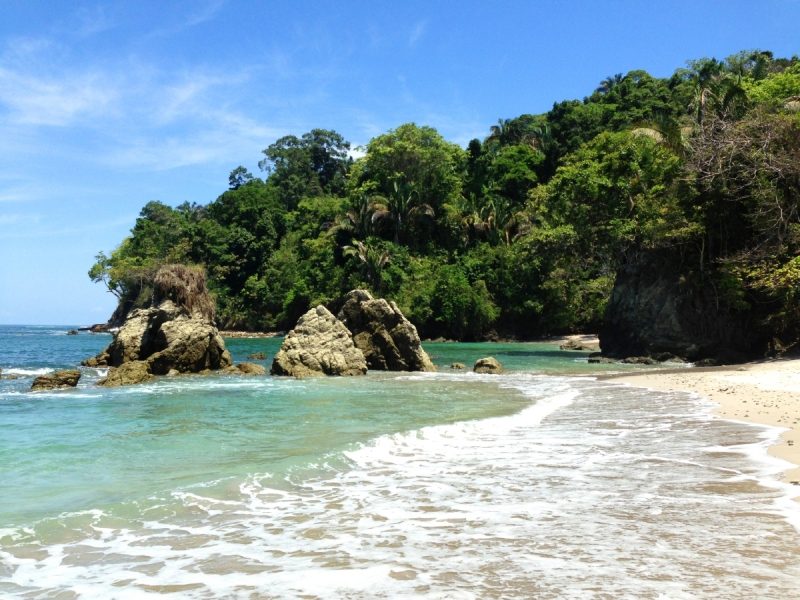 The turquoise waters in Playa Manuel Antonio with luscious forest in the distance