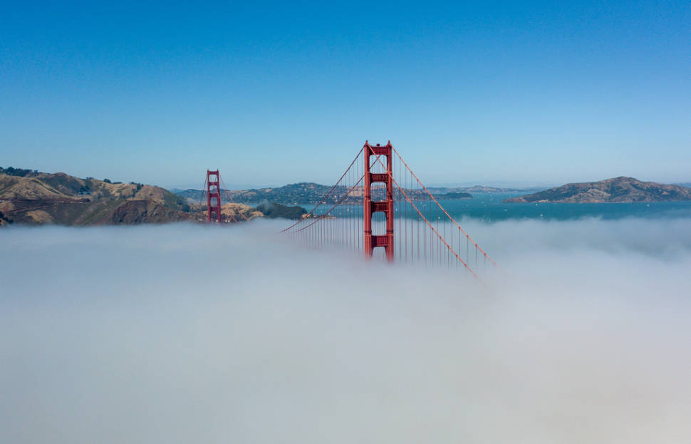The dense fog covers up half of the Golden Gate Bridge