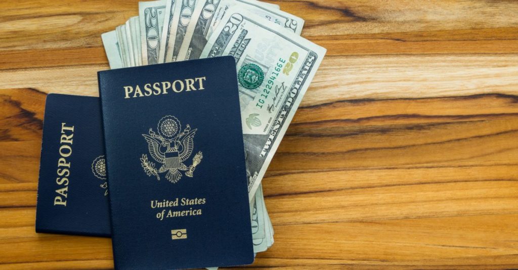 Dollar bills tucked into an American passport on a desk