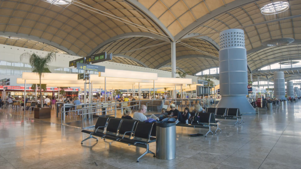 An airport terminal with benches for people to sit in