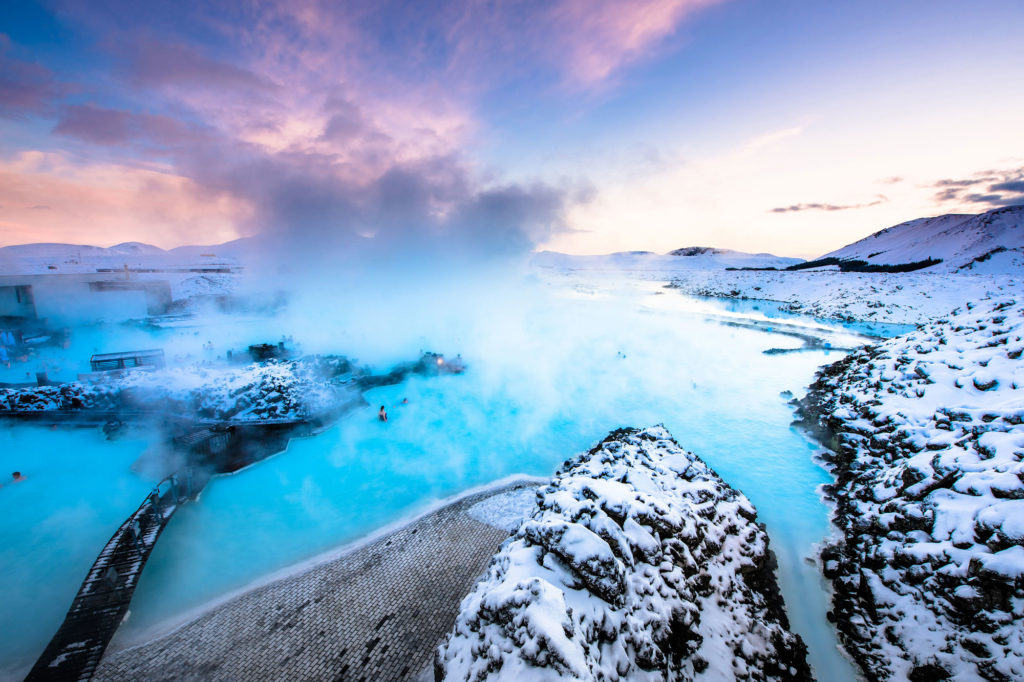 The blue lagoon stretches out and is protected by snow-topped mountains