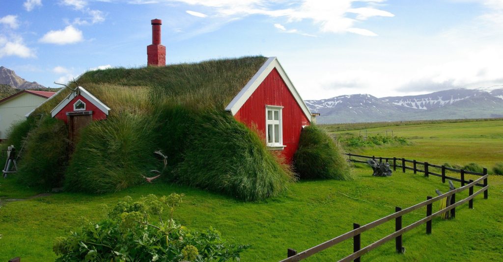 A red house covered in moss and grass characteristic of some Icelandic villages